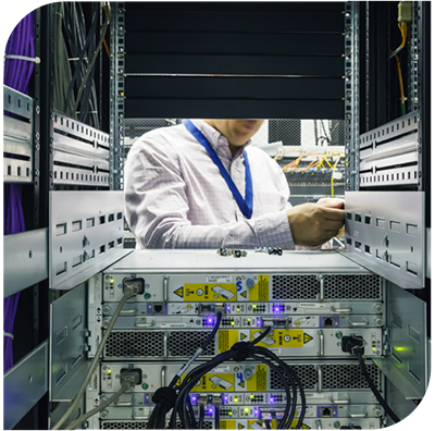 Man using tools to service a sever. View from behind server rack